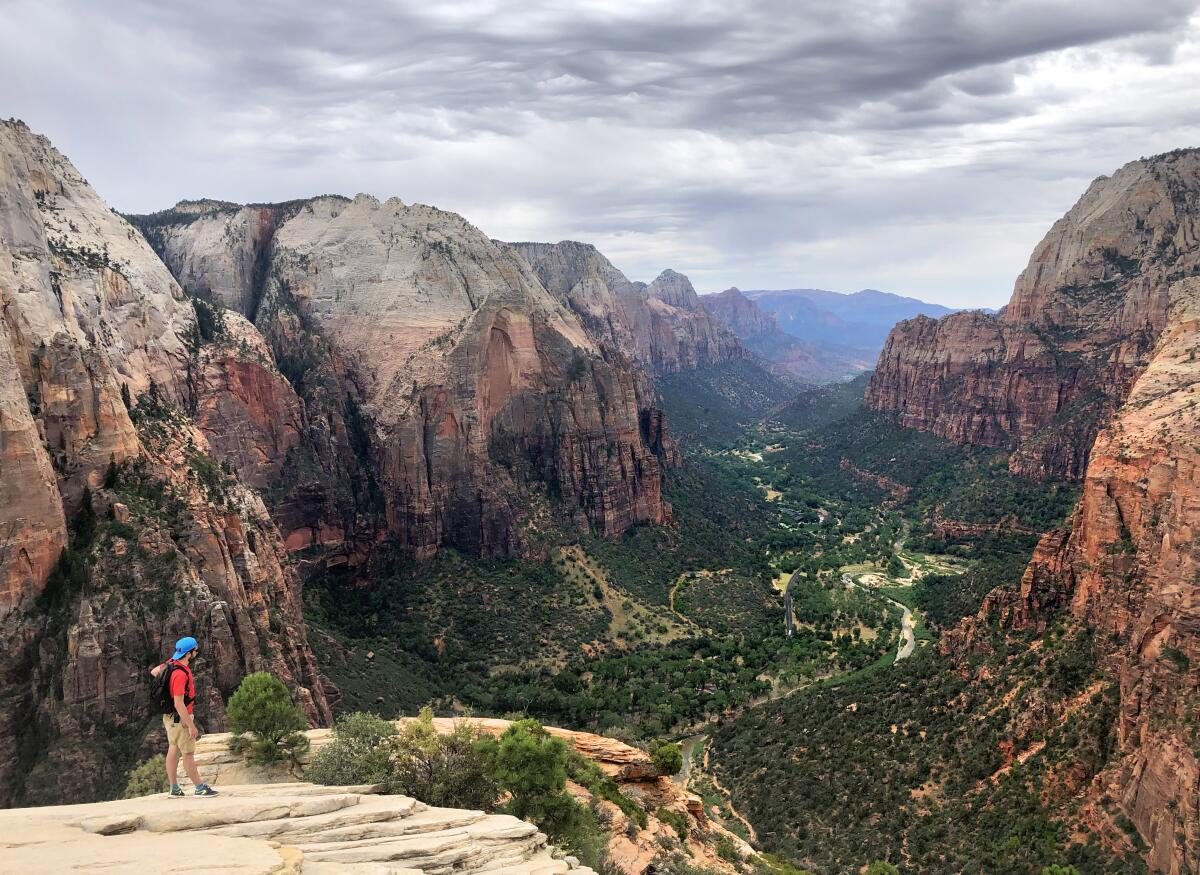 A hiker takes in the view from the top of Angels Landing in Utah’s Zion National Park.