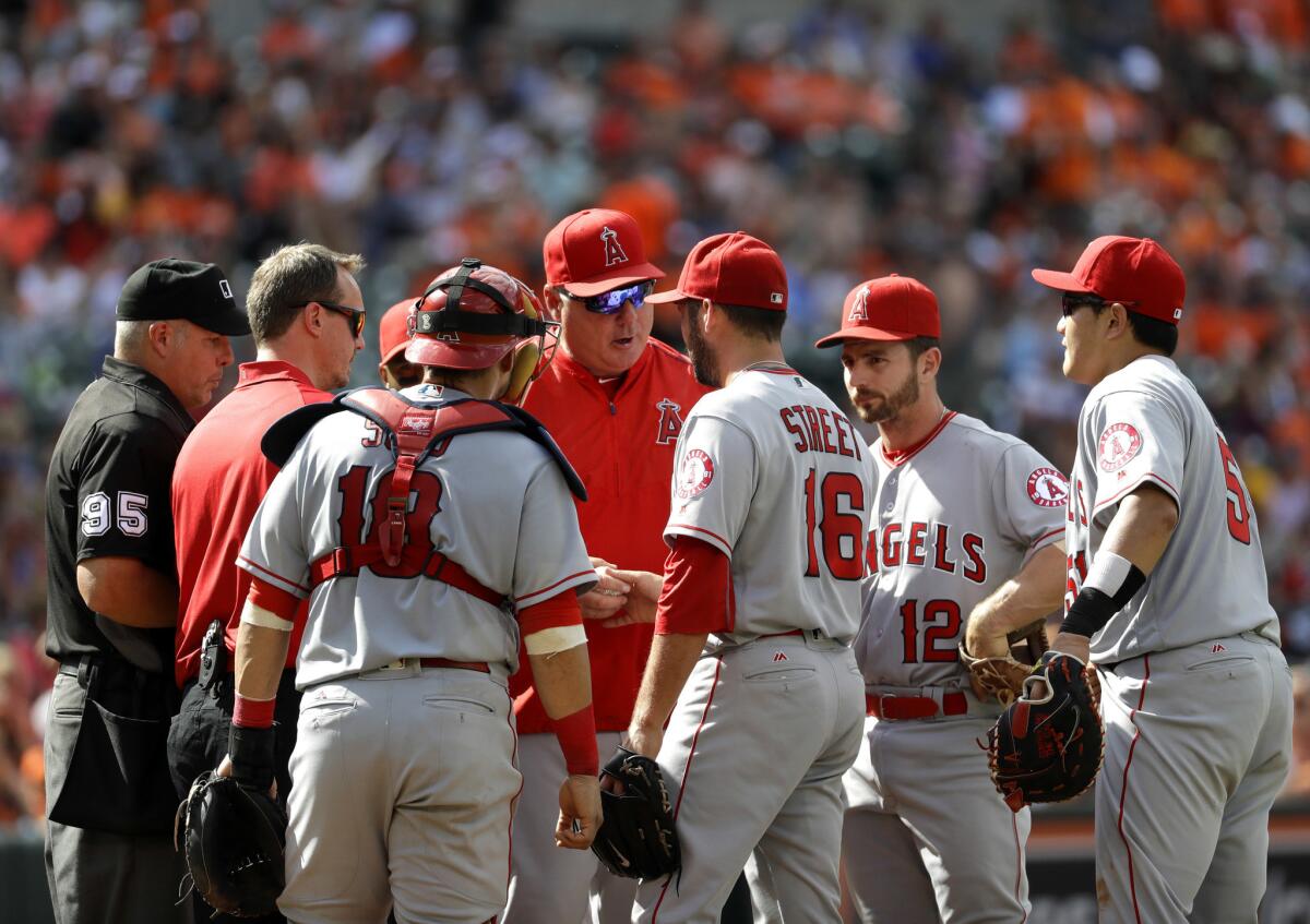 Angels Manager Mike Scioscia, center, takes out closer Huston Street (16) in the eighth inning because of cramps in the left hamstring.