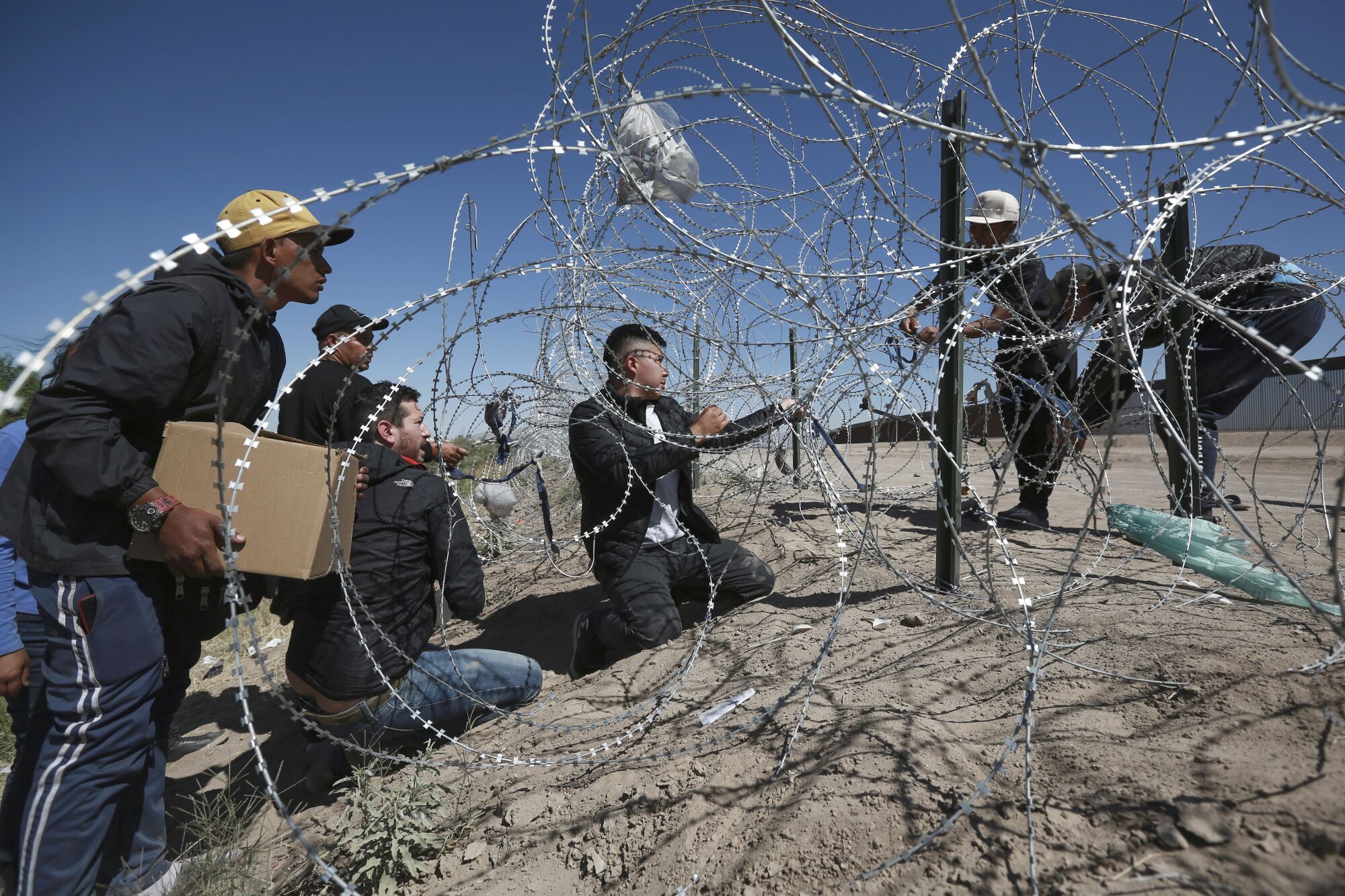 Migrants cross the barbed wire barrier into the United States from Ciudad Juarez, Mexico.