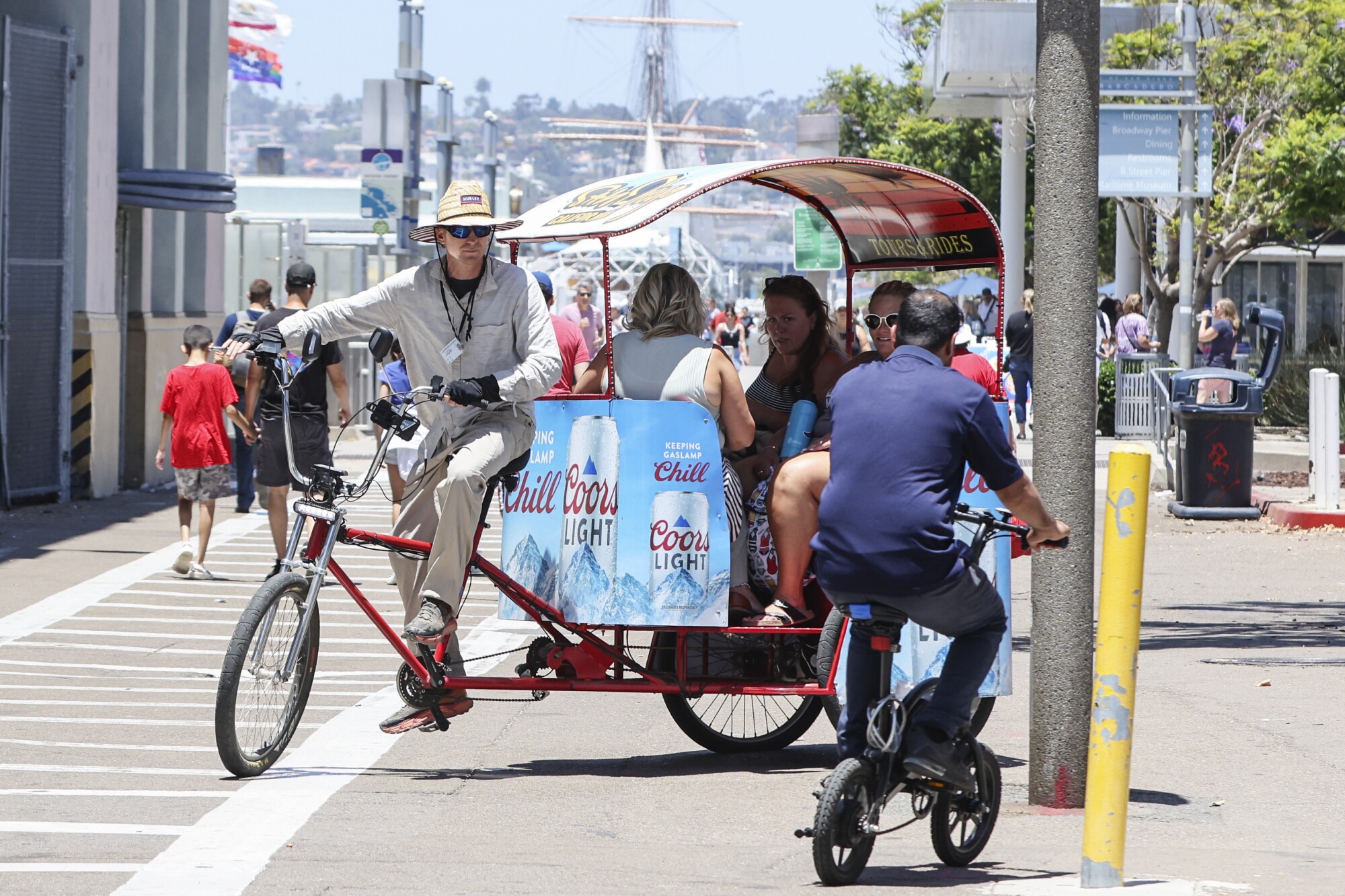 With a power assist Pedicab, a driver negotiates traffic after picking up riders by the USS Midway Museum.