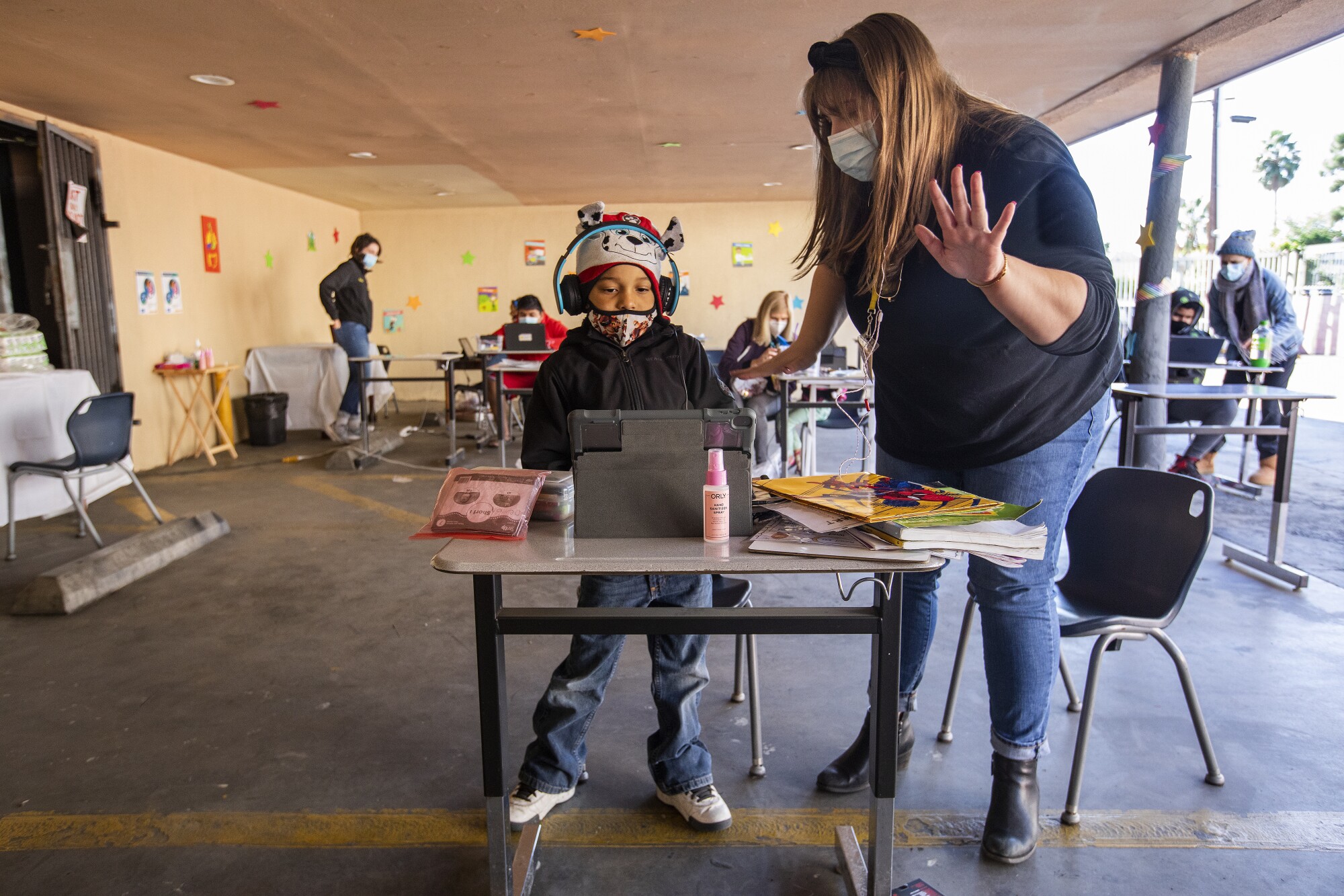 Volunteer Elyse Stelford helps a 6-year-old learn math at a learning pod for homeless children, at the Hyland Motel