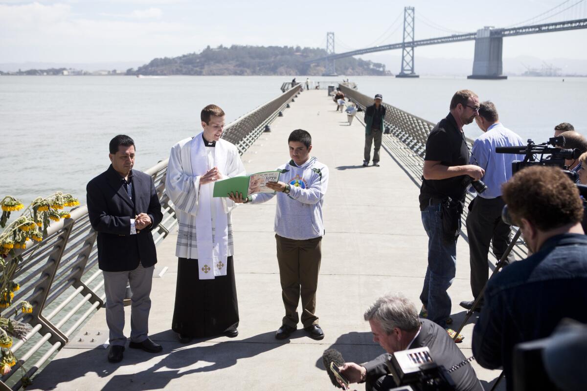 Father Cameron Faller, second left, of Restorative Justice Ministry conducts a vigil for Kathryn Steinle, July 6, 2015, on Pier 14 in San Francisco. Steinle was gunned down on July 1, while out for an evening stroll at Pier 14 with her father and a family friend.