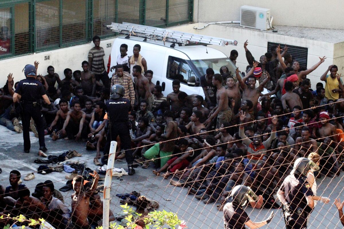 Police watch over some of the hundreds of migrants that managed to get past the border fence in Ceuta, a Spanish enclave bordering Morocco, in July 2018.