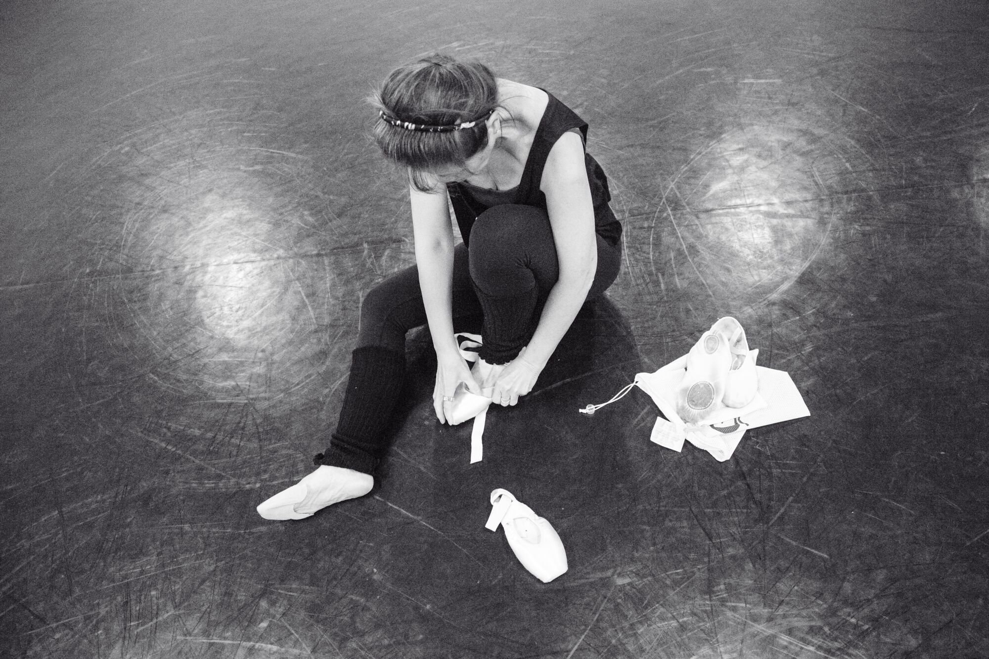 A dancer tying ballet shoes in the studio.