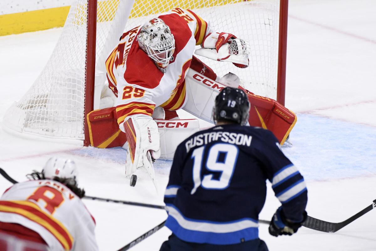 Calgary Flames goaltender Jacob Markstrom (25) makes a save on Winnipeg Jets' David Gustafsson (19) during the first period of an NHL hockey game Tuesday, Jan. 3, 2023, in Winnipeg, Manitoba. (Fred Greenslade/The Canadian Press via AP)