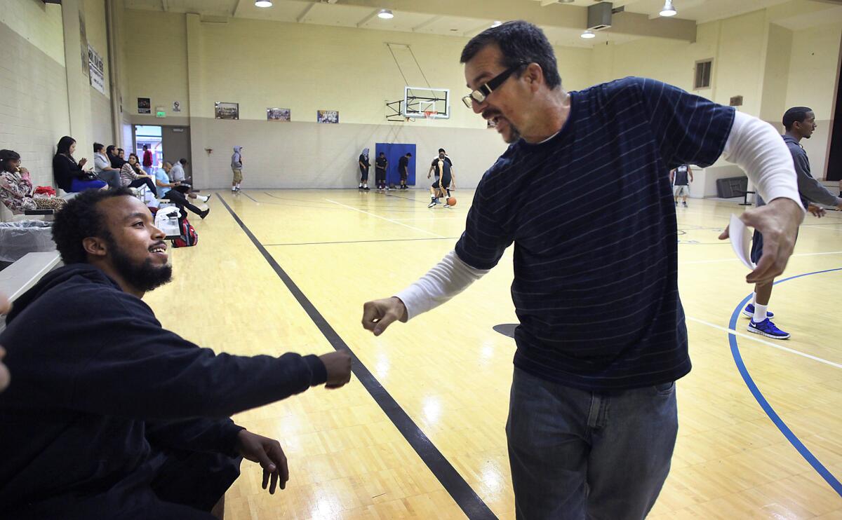 C.J. Johnson, left, fist bumps gang intervention worker George Sarabia inside the gymnasium. "C.J. opened a door," Sarabia said. "I told him, 'You know what I want to do. I can't do it without you. We've got to break that barrier.'"