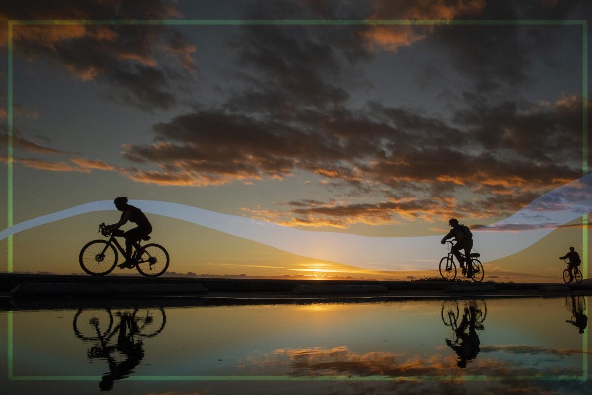 Cyclists are reflected in a puddle left from recent rains as the sun sets at Will Rogers State Beach.