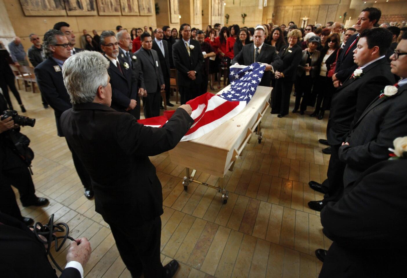 Relatives watch as the American flag is placed over the simple pine casket of teacher Sal Castro.