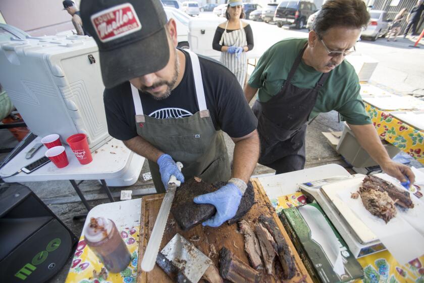 Andrew Muñoz, owner of Moo's Craft Barbecue, and his father prepare orders at a pop-up event outside Indie Brewing Company.