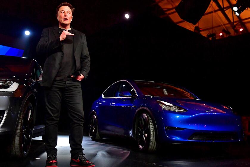 Tesla CEO Elon Musk speaks beside the new Tesla Model Y, right, after introducing it at the Tesla Design Studio in Hawthorne, Calif. on Mar. 14, 2019.