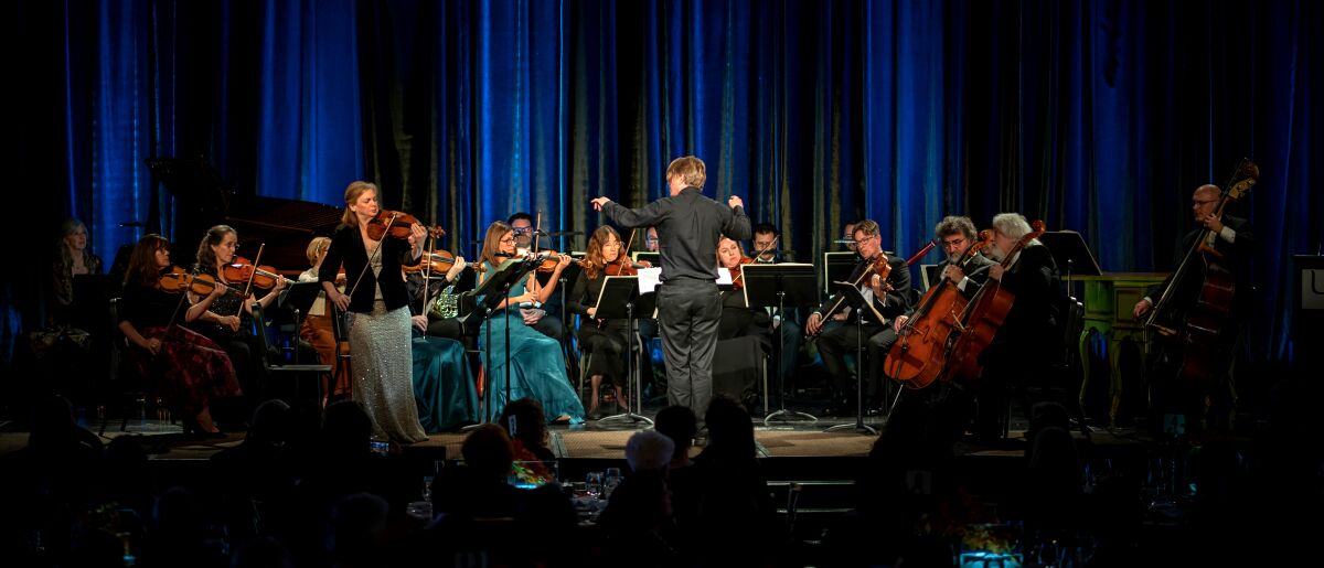 A conductor faces a group of musicians.