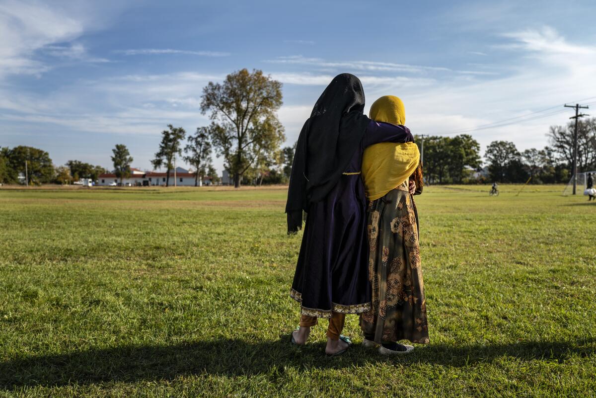 Afghan evacuees watch a soccer game on a grassy field