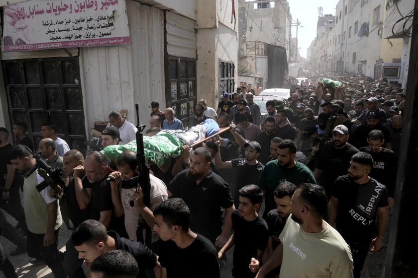 Gunmen march during a funeral with the bodies of Palestinians Ahmed Abu Arra from the town of Aqaba, left, and Raafat Dawasa from the town of Silat Al-Harithiya, both draped in the Hamas flag and killed in an Israeli strike in the Jenin refugee camp, in the West Bank city of Jenin, Sunday, Aug. 18, 2024. Israel's military said Saturday it struck a "terrorist cell" in Jenin. The Palestinian health ministry there said two bodies were taken to a government hospital; Hamas claimed the two men as commanders in its military wing. (AP Photo/Majdi Mohammed)