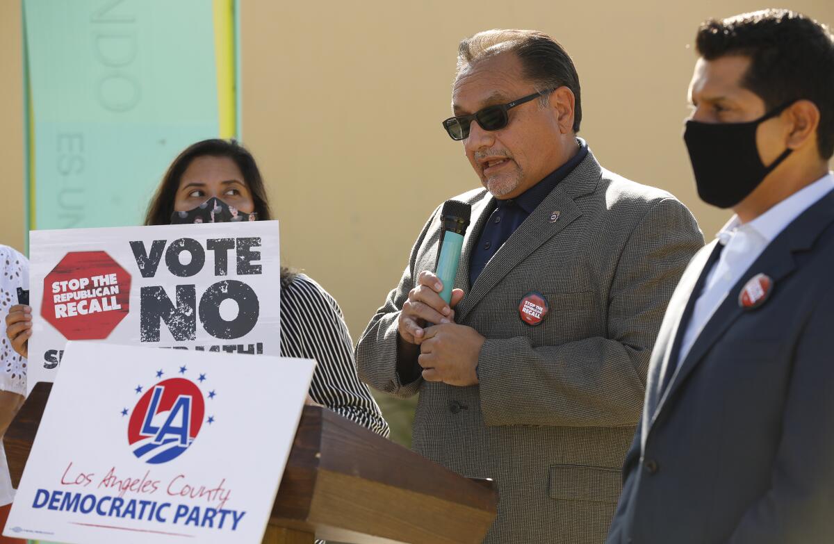 Ron Herrera holding a microphone speaking at a lectern