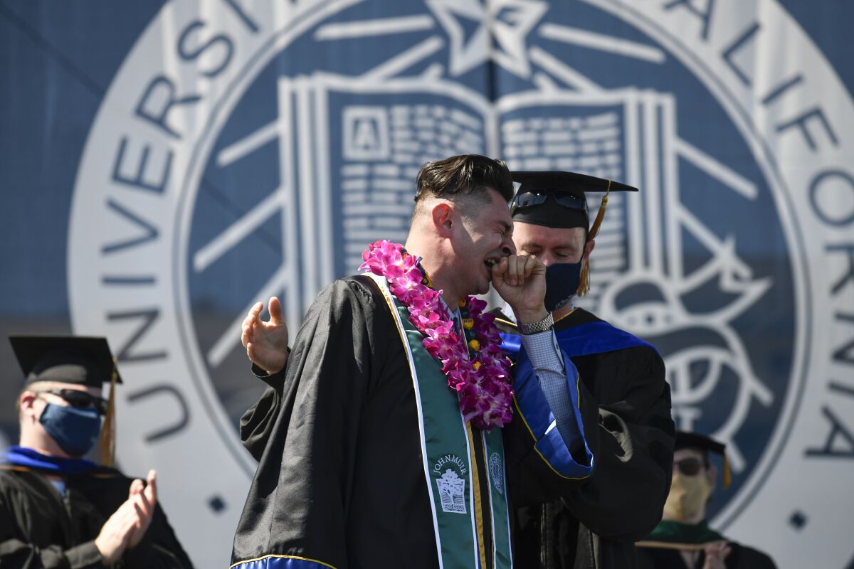 UC San Diego graduate Alex Rodriquez (left) cries after speaking at the Muir College commencement ceremony on June 12.