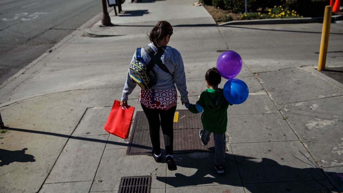 A Salvadoran immigrant who is in the U.S. illegally walks with her son, 5, and daughter (not visible in a carrier) after paying gas and power bills.