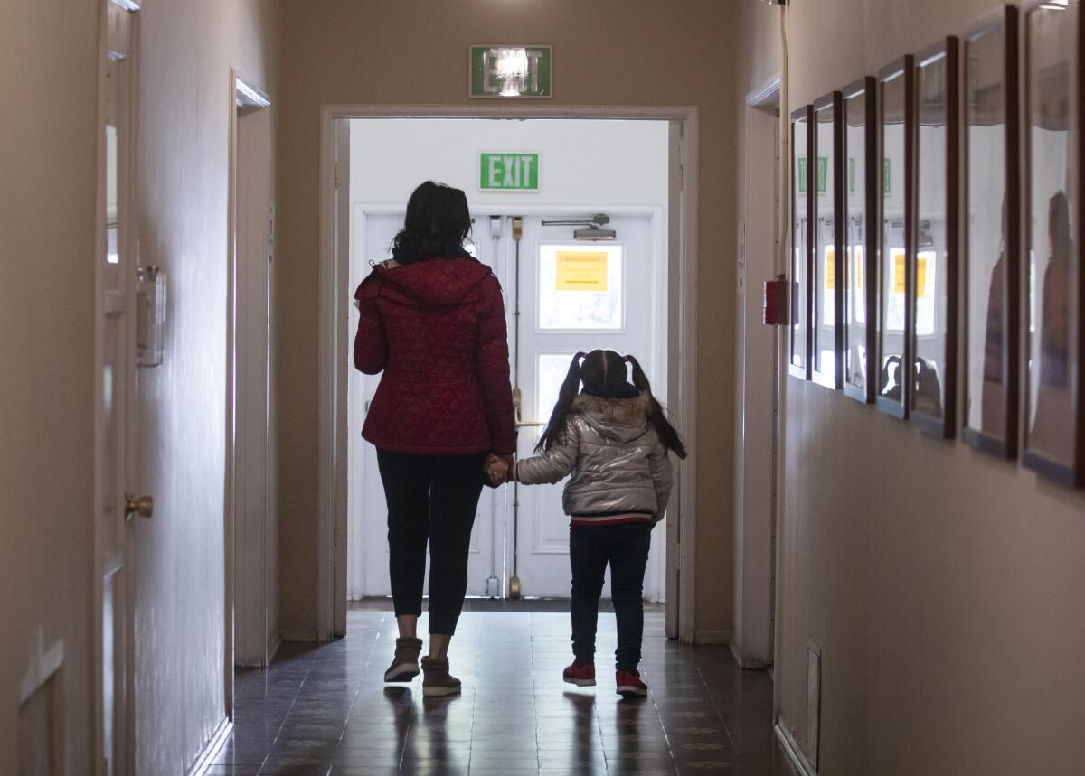 A case manager for domestic violence victims walks with her 5-year-old daughter.