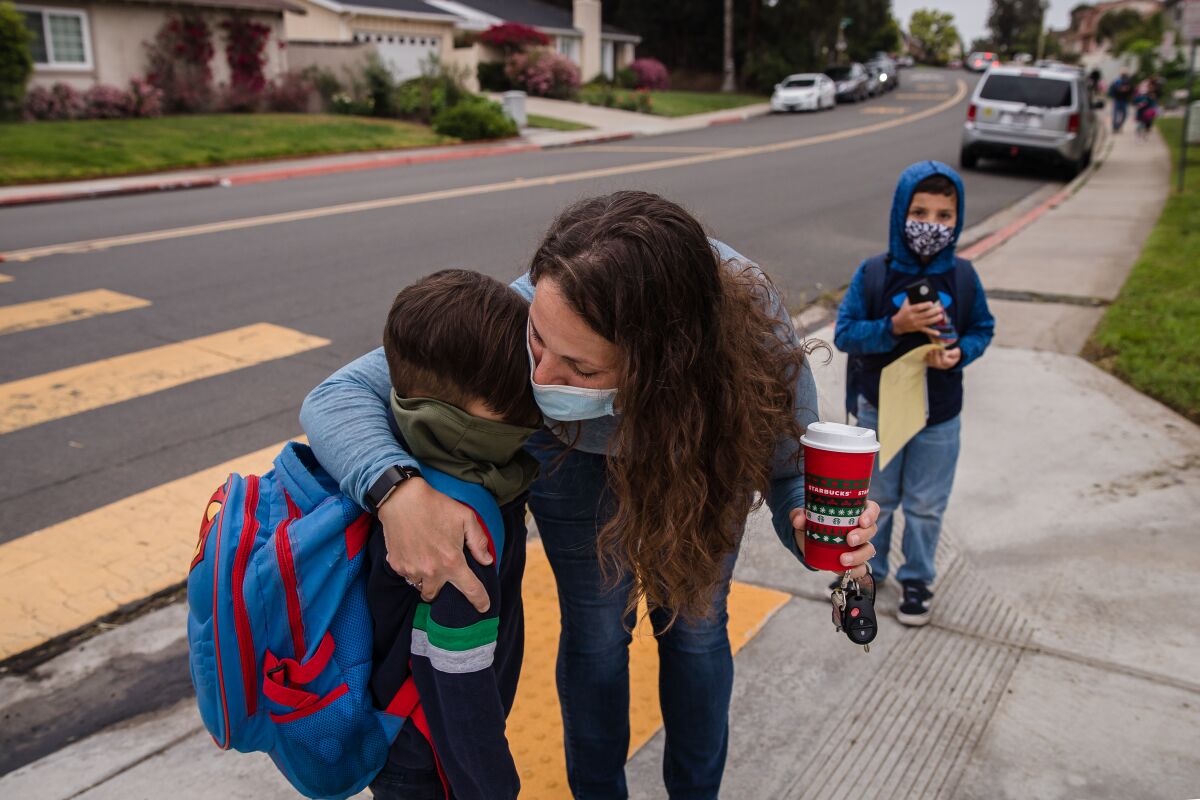 Andrea Morales hugs her son Reece while her son Keiran stands near Tierrasanta Elementary