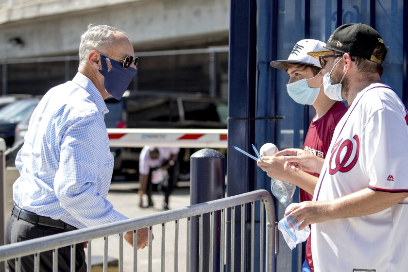 MLB Commissioner Rob Manfred, left, speaks with fans as he arrives at Nationals Park for the New York Yankees and the Washington Nationals opening day baseball game, Thursday, July 23, 2020, in Washington. (AP Photo/Andrew Harnik)