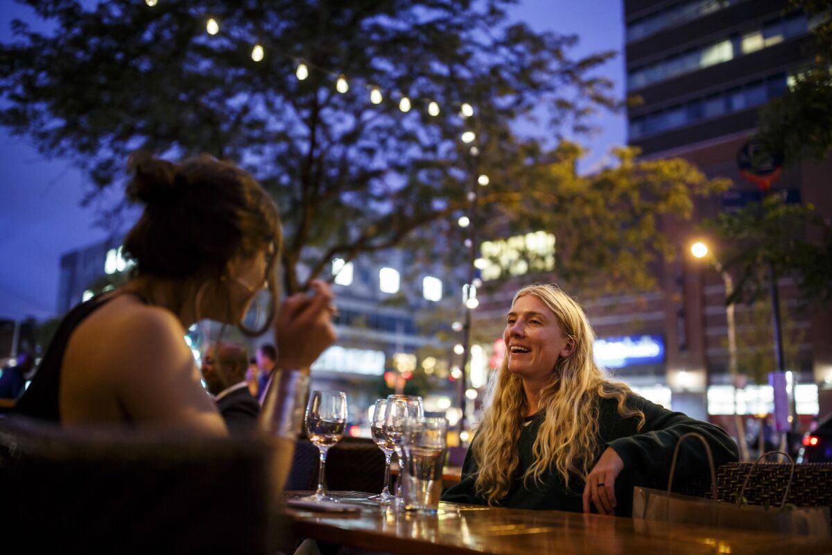 Liana Satenstein, left, and Emily Rosser enjoy drinks on a breezy and cool evening on the outside patio at Red Rooster Harlem.