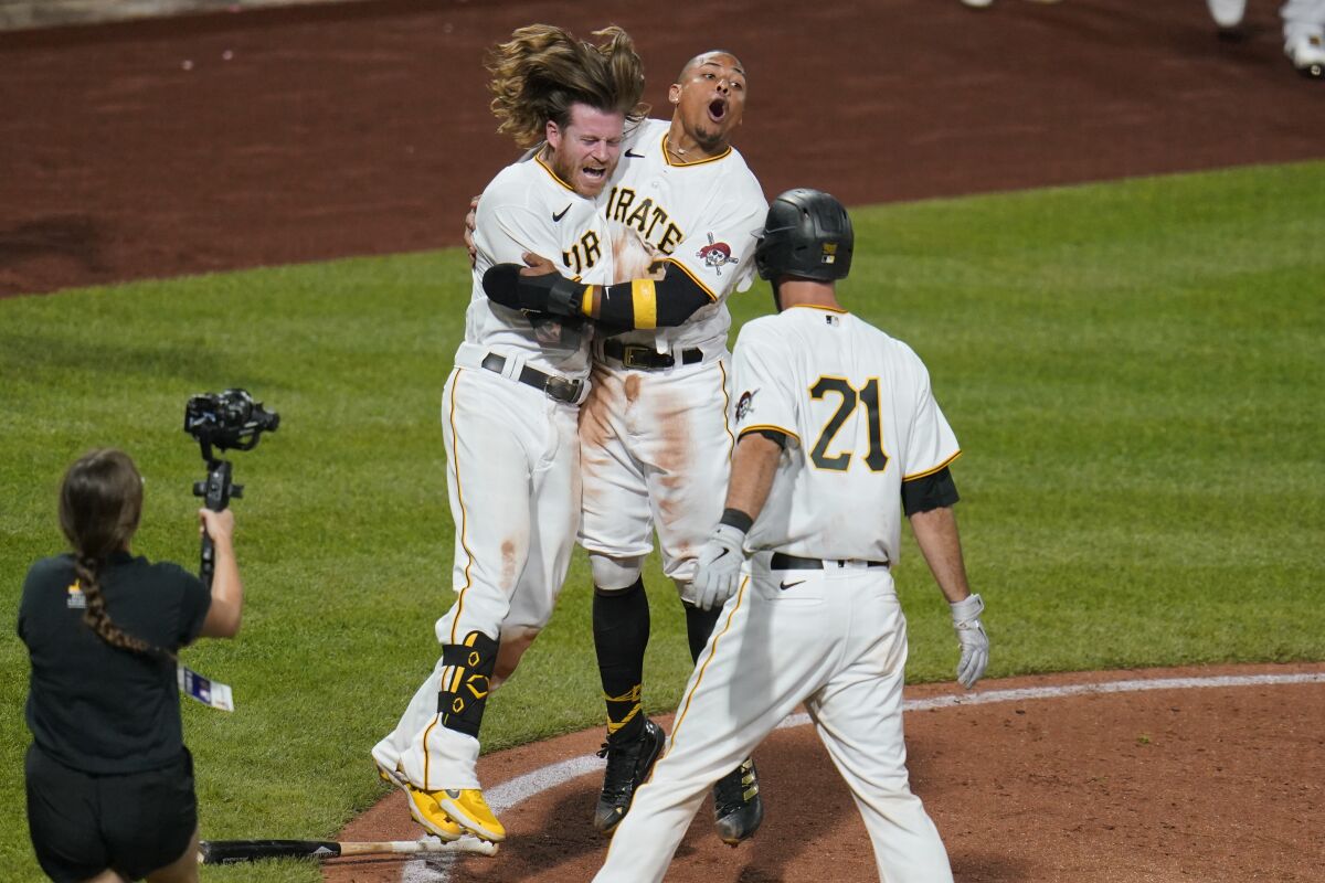 Pittsburgh Pirates' Wilmer Difo, back right, and Ben Gamel, back left, celebrate after Difo scored from second on a groundout by Colin Moran to give the Pirates a 5-4 win in a baseball game against the Cincinnati Reds in Pittsburgh, Wednesday, Sept. 15, 2021. (AP Photo/Gene J. Puskar)
