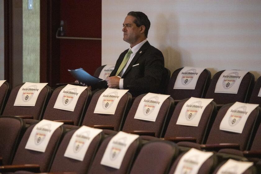 SANTA ANA, CALIF. -- TUESDAY, MARCH 17, 2020: Surrounded by social distancing signs, Orange County District Attorney Todd Spitzer listens before addressing the Orange County supervisors during a discussion on the county's latest efforts to combat the coronavirus pandemic at the Hall of Administration in Santa Ana, Calif., on March 17, 2020. (Allen J. Schaben / Los Angeles Times)