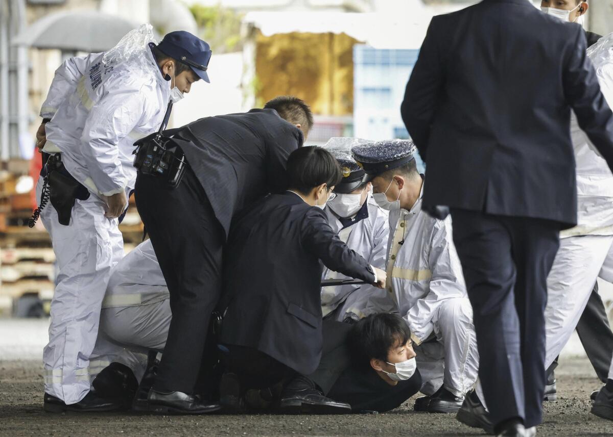 A man is held on the ground by police.