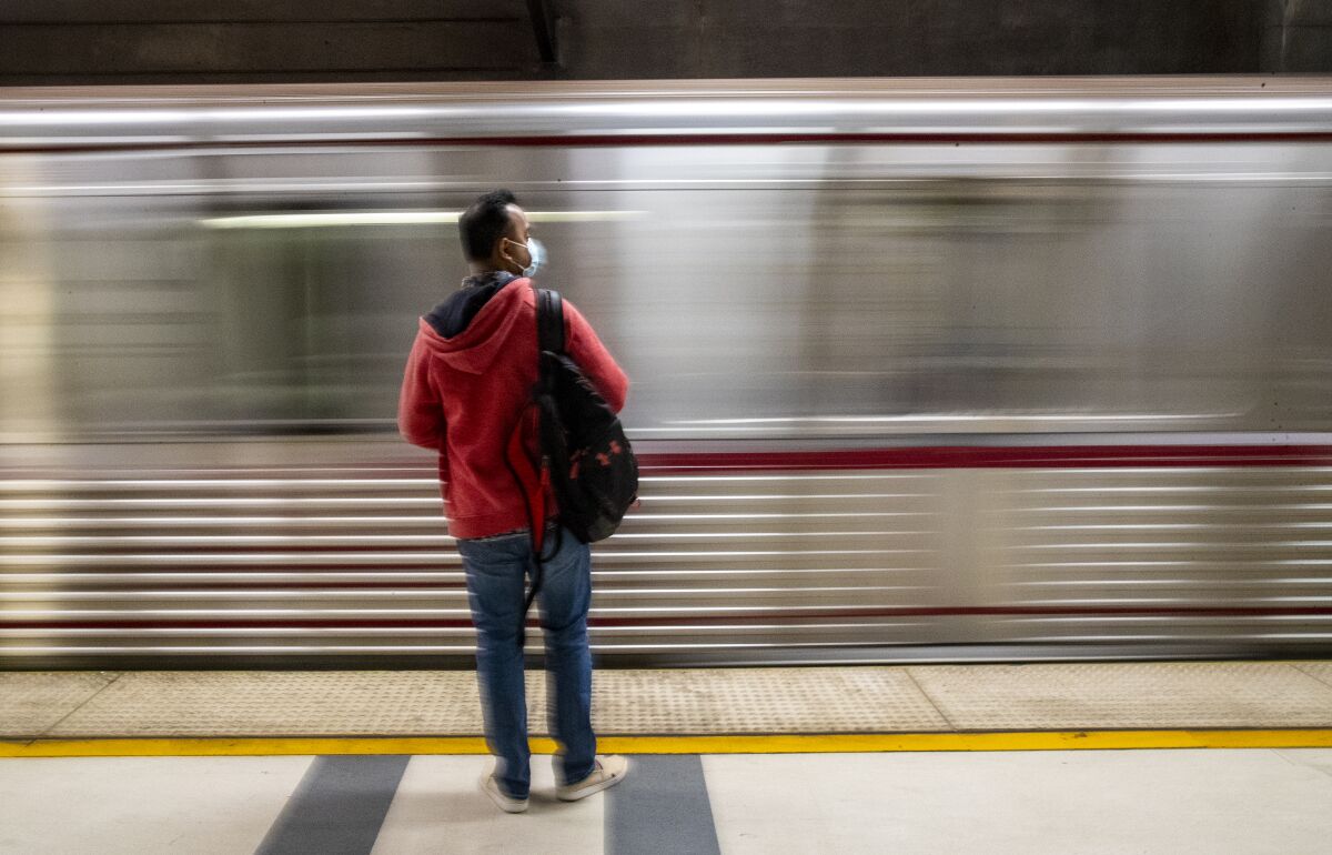 A commuter waits at Pershing Square station as a Metro Red Line train arrives 