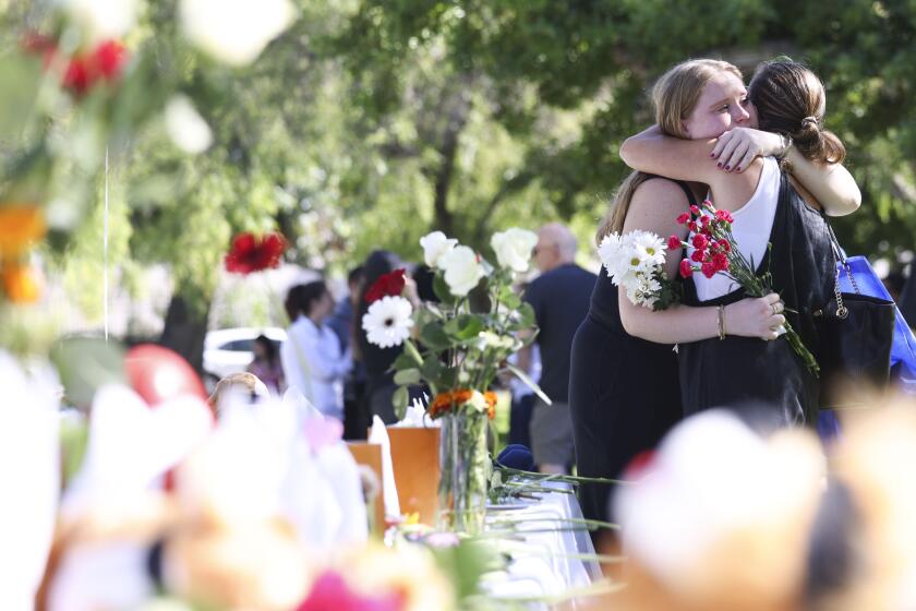San Diego, CA - October 28: Demi Batten comforts her mother Tracey as they place flowers at a Shabbat dinner table with 220 empty seats for every Israeli being held hostage by Hamas at Balboa Park on Saturday, Oct. 28, 2023 in San Diego, CA. (Meg McLaughlin / The San Diego Union-Tribune)