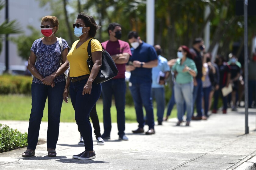 People line up outside the Miramar Convention Center for the first mass vaccination event carried out by the Department of Health and the Voces nonprofit organization, seeking to apply 10,000 Johnson and Johnson vaccines, in San Juan, Puerto Rico, Wednesday, March 31, 2021. (AP Photo/Carlos Giusti)