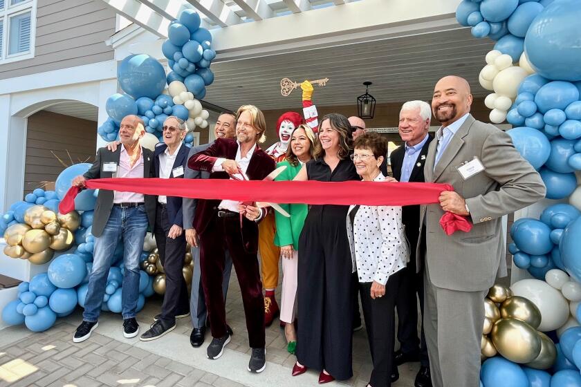 Charles Antis cuts the ribbon at Ronald McDonald House Orange County along with Ronald McDonald and other RMHC board members.