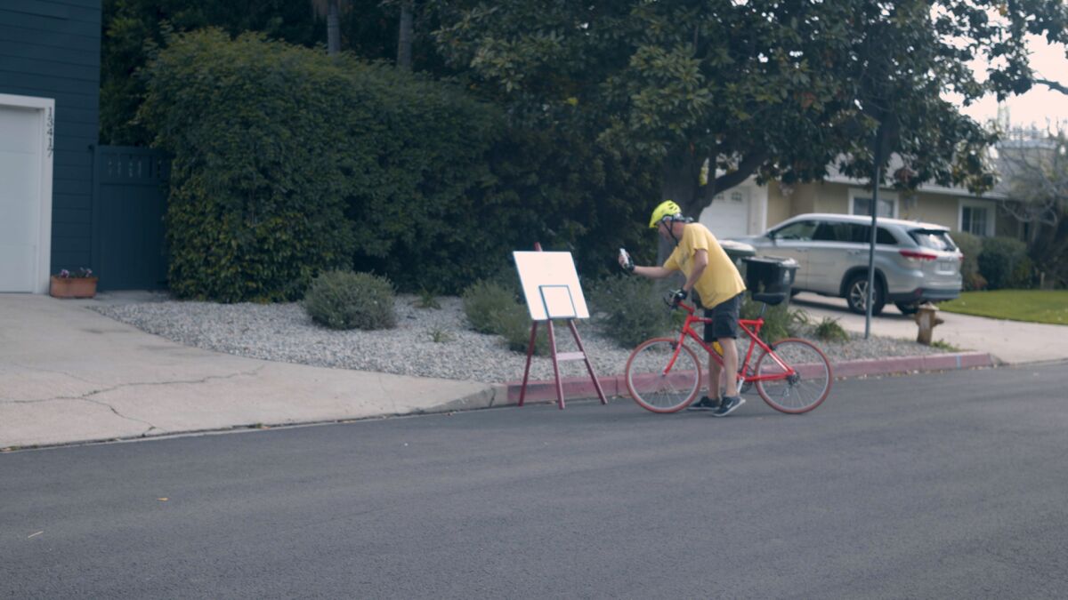 Chris Johnsten stops on his bicycle to take a photo of artist Kathryn Pitt's daily painting.