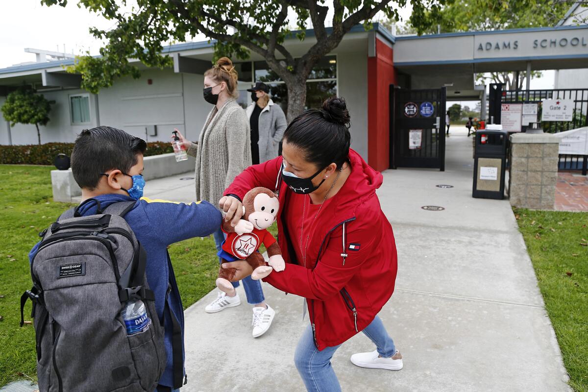 Frances Garcia greets a student Wednesday on the first full day of instruction at Adams Elementary School in Costa Mesa.