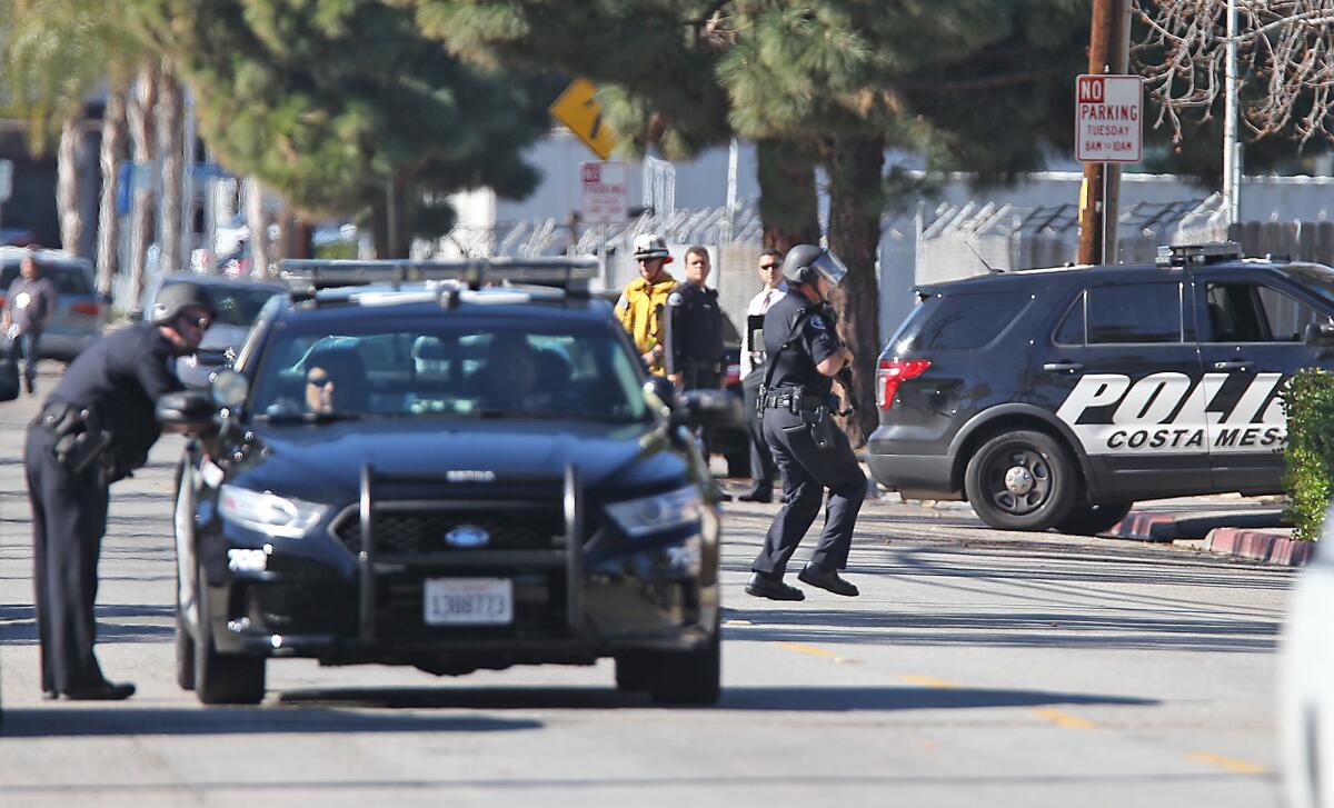Costa Mesa police officers work the scene of a standoff with an armed teenager Tuesday morning.