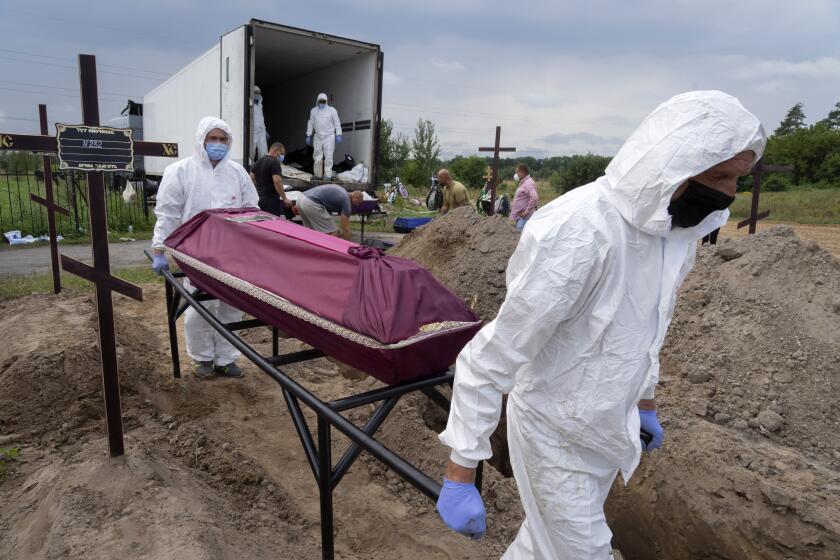 Workers carry a coffin with unidentified remains of a civilian murdered by the Russian troops during Russian occupation in Bucha, on the outskirts of Kyiv, Ukraine, Thursday, Aug. 11, 2022. Eleven unidentified bodies exhumed from a mass grave were buried in Bucha Thursday. (AP Photo/Efrem Lukatsky)