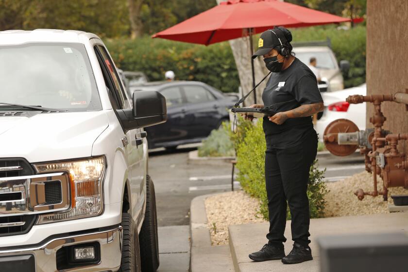 AGOURA HILLS, CA - AUGUST 18: Betzy Gutierrez takes customer orders for the drive-through window of the El Pollo Loco restaurant in Agoura Hills on August 18, 2021. Michaela Mendelsohn, CEO of Pollo West Corp, an Agoura Hills-based franchise company for Pollo Loco owns six restaurants with 200 employees in LA and Ventura Counties. When the pandemic hit in March 2020, Mendelsohn laid off 25 workers but was able to rehire them within weeks thanks to a federal loan. Her business lost sales at the beginning of the pandemic but revenue is now 10% above pre-pandemic levels. Five of her 6 outlets have drive-through which allowed business to continue. She has avoided labor shortages by raising wages, giving bonuses to employees who kept working through the pandemic, and expanding paid time off. Nonetheless, she is concerned that new COVID variants, the failure of many to get vaccinated, expiring unemployment benefits and expiring eviction protections could set back California's economy again. El Pollo Loco on Wednesday, Aug. 18, 2021 in Agoura Hills, CA. (Al Seib / Los Angeles Times).