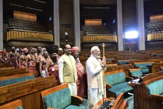 El primer ministro indio, Narendra Modi, lleva un cetro dorado para colocarlo junto a la silla del presidente de la cámara en el inicio de la ceremonia inaugural del nuevo edificio del parlamento, en Nueva Delhi, India, el domingo 28 de mayo de 2023. (AP Foto)