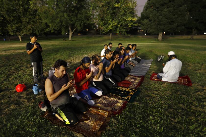 Sacramento, California-Afghan men gather in prayer at a park in Sacramento, California, on Aug. 18, 2021. Many come to the park each night to play sports together. The Afghan community of Sacramento is one of the largest in the United States. Many Afghan living in the United States worry about their relatives in Afghanistan and what will happen now that the Taliban is back in control. (Carolyn Cole / Los Angeles Times)
