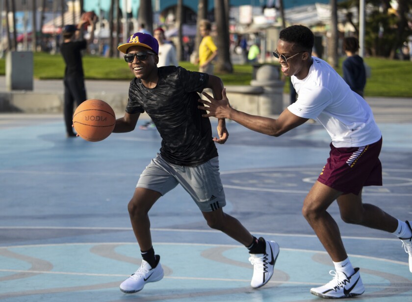 Marcus Bowen, 13, left, drives on brother Dante Bowen, 16, on the public courts during pickup games in Venice. The brothers from Toronto said they were trying to channel the moves of Kobe Bryant.