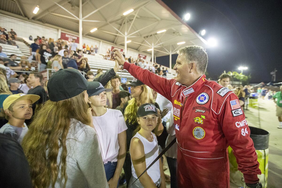 Costa Mesa Fire Chief Dan Stefano gets a high-five at the Orange County Fair's Motorhome Madness demolition derby Friday night. Stefano competed against four other area fire and police chiefs.