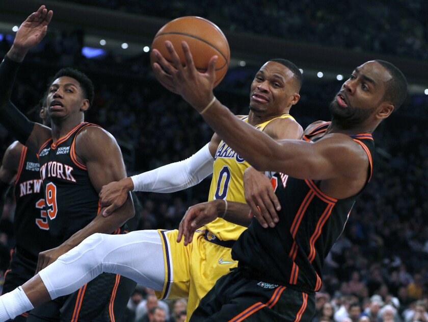 Lakers guard Russell Westbrook and New York Knicks guard Alec Burks vie for a rebound as RJ Barrett watches.