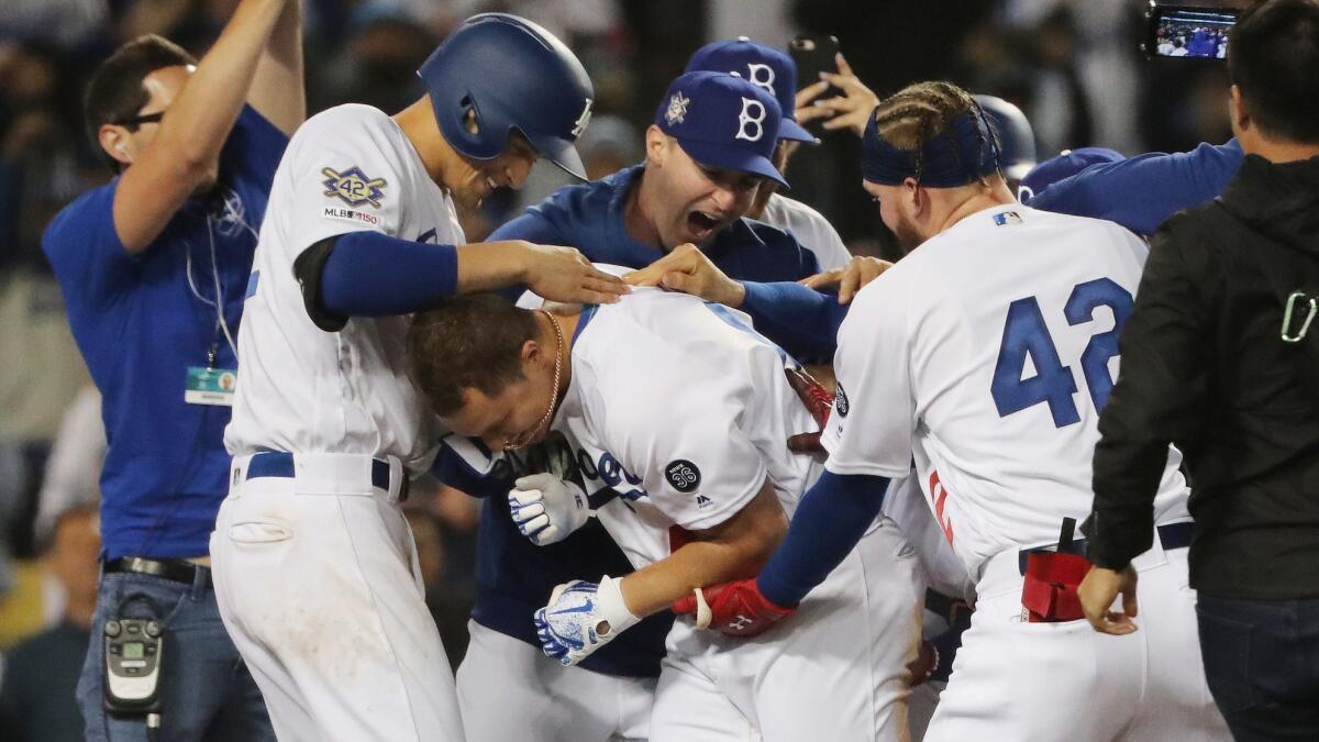 Joc Pederson, center, is mobbed by Dodgers teammates after hitting a walk-off homer to beat the Cincinnati Reds, 4-3, on Monday at Dodger Stadium.