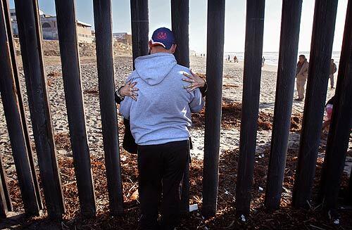 Fernando Orozco and his wife, Marta Ramos, embrace through the iron posts of the U.S.-Mexico border fence. Orozco is a legal U.S. resident who works in Santa Monica; his wife is a Mexican citizen. When construction of a second parallel fence through Border Field State Park is completed later this year, reunions like this won't be possible.