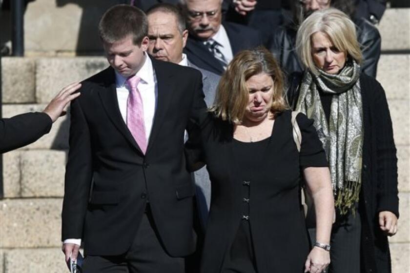 A mourner reaches out to Daniel Ritzer, brother of slain Danvers High School teacher Colleen Ritzer, as he accompanies his mother, Peggie, out of St. Augustine Church in Andover, Mass., Monday Oct. 28, 2013, after Colleen Ritzer's funeral service. Ritzer, 24, who taught math at Danvers High School, was killed in a school bathroom after dismissal Tuesday, police said. Her body was found in woods behind the school, and student Philip Chism, 14, has been arrested in connection with Ritzer's murder.