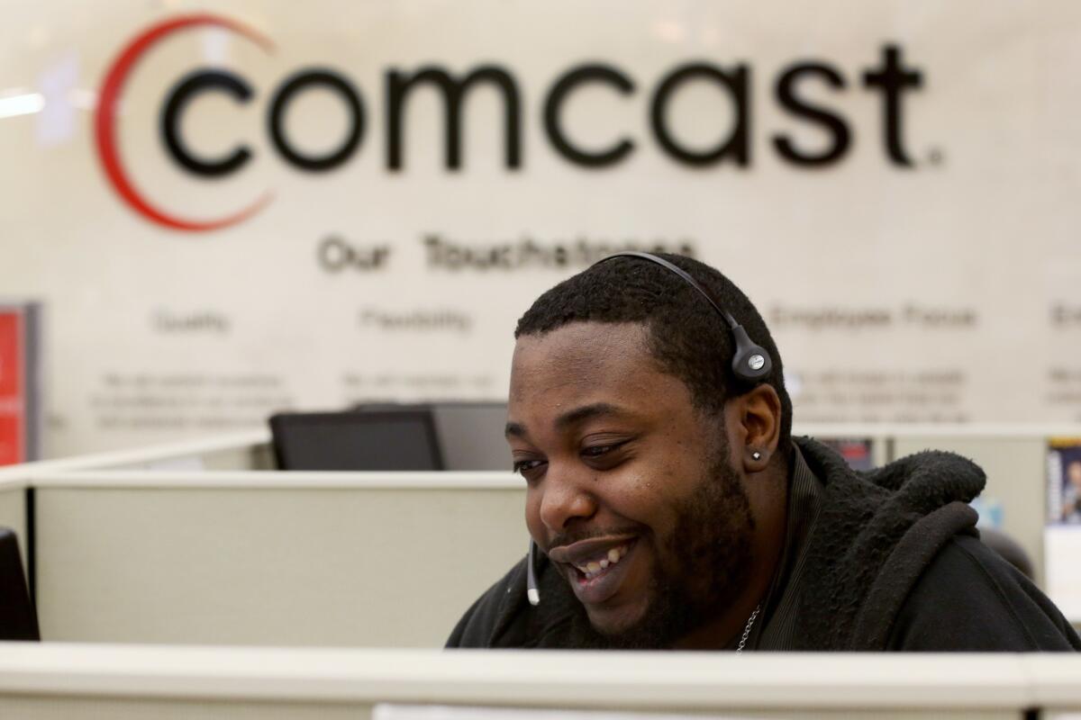 Gregory Bristol, a customer associate, speaks with a customer on the phone at a Comcast cable call center in Miramar, Fla. On Thursday, Comcast announced a $45-billion deal to buy Time Warner Cable.
