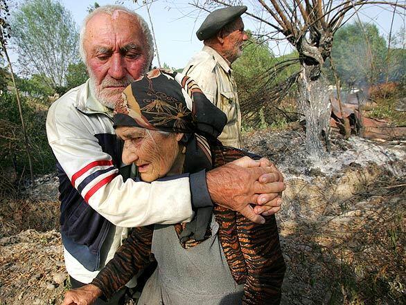 Elderly ethnic Georgians stand near their burned home in the village of Avnevi in South Ossetia. Satellite images obtained by the United Nations and reports from researchers show that ethnic Georgian villages inside South Ossetia were deliberately torched, Human Rights Watch said.