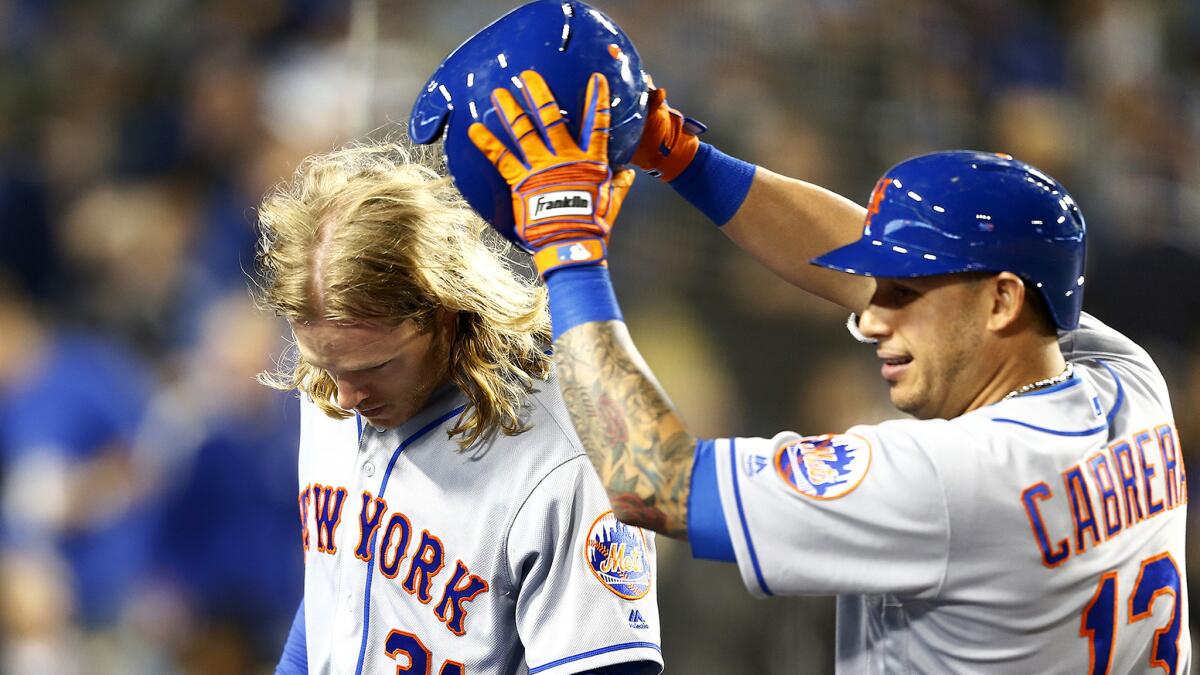 Mets starter Noah Syndergaard has his helmet removed by shortstop Asdrubal Cabrera (13) after hitting a three-run home run against the Dodgers in the fifth inning Wednesdsay night.