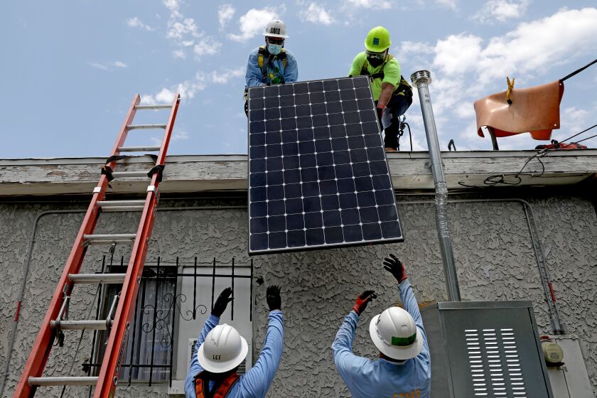 LOS ANGELES, CA - JUNE 18: David Andrade, top left, work force training specialist, Juan Alcantara, intern/trainee, right, Lee Kwok, bottom left, solar installer supervisor, and Darean Nguyen, senior solar installation supervisor, of GRID Alternatives, a nonprofit, install solar panels that will generate 5 kilowatts of energy at a low-income home in Watts on Friday, June 18, 2021 in Los Angeles, CA. A total of 15 327 watt panels were placed on the roof. (Gary Coronado / Los Angeles Times)