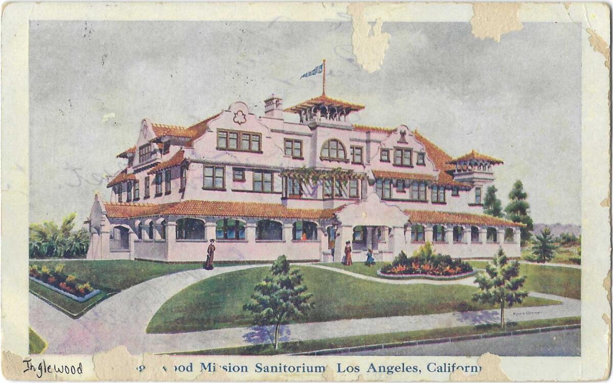 A pink, Mission-style building with tiled roof on a postcard with decades of wear