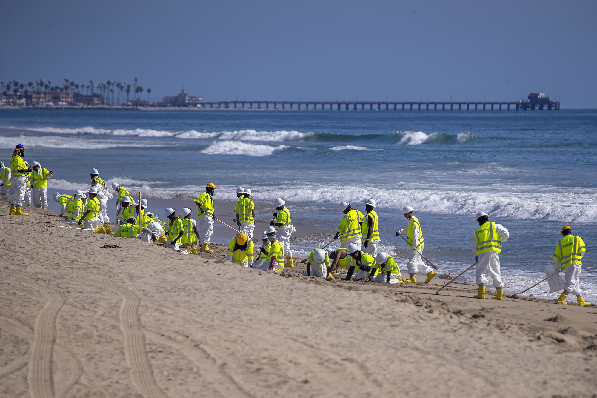 Cleanup crews in yellow vests on the beach